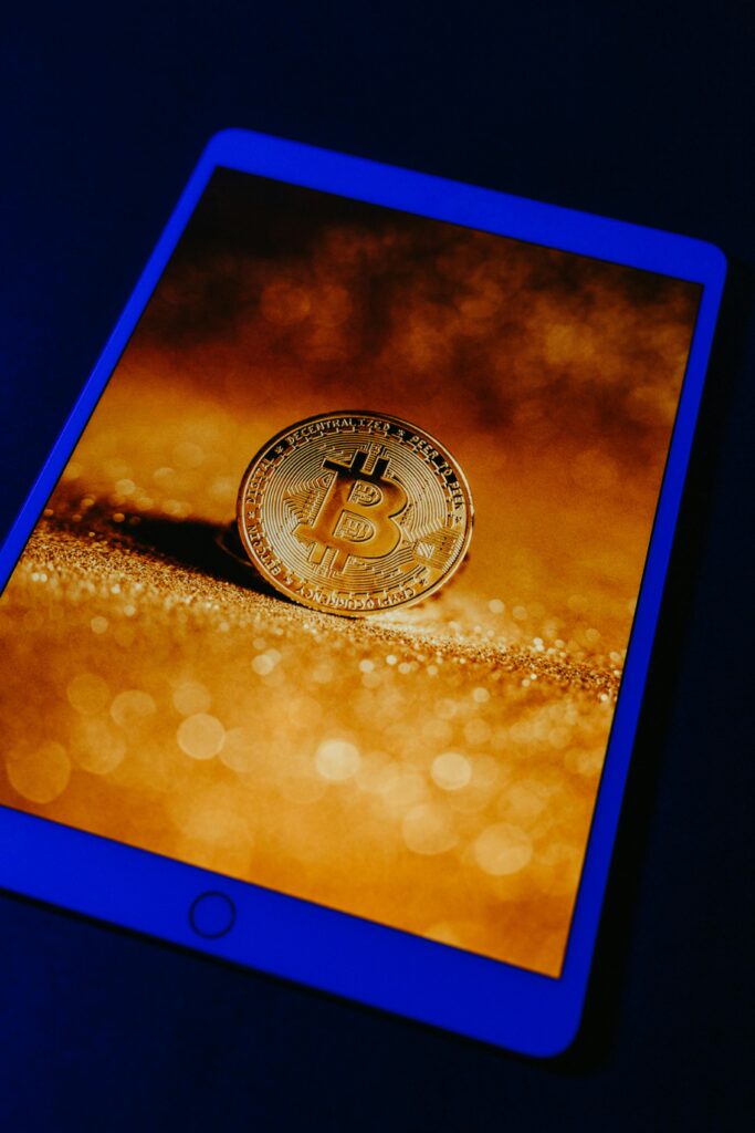 NFTs Explained: Do They Still Matter in 2024 A golden Bitcoin coin displayed digitally on a tablet screen, representing digital currency and blockchain technology.