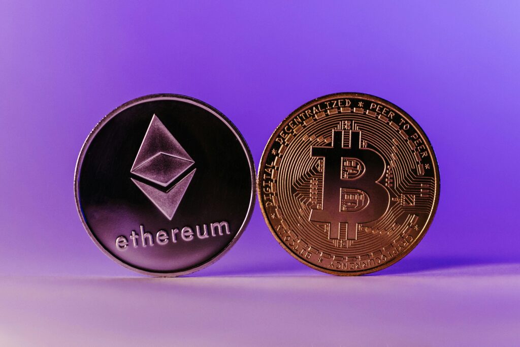 Bitcoin vs Ethereum: What Should You Buy First Close-up of Ethereum and Bitcoin coins symbolizing cryptocurrency and blockchain technology against a purple backdrop.