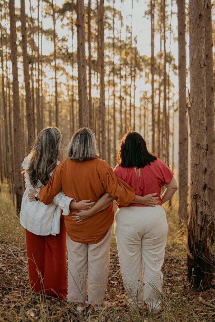 To All My Beautiful Crypto Mama's - This One Is For You Three women embracing in a forest during dusk in São Paulo, symbolizing friendship and support.