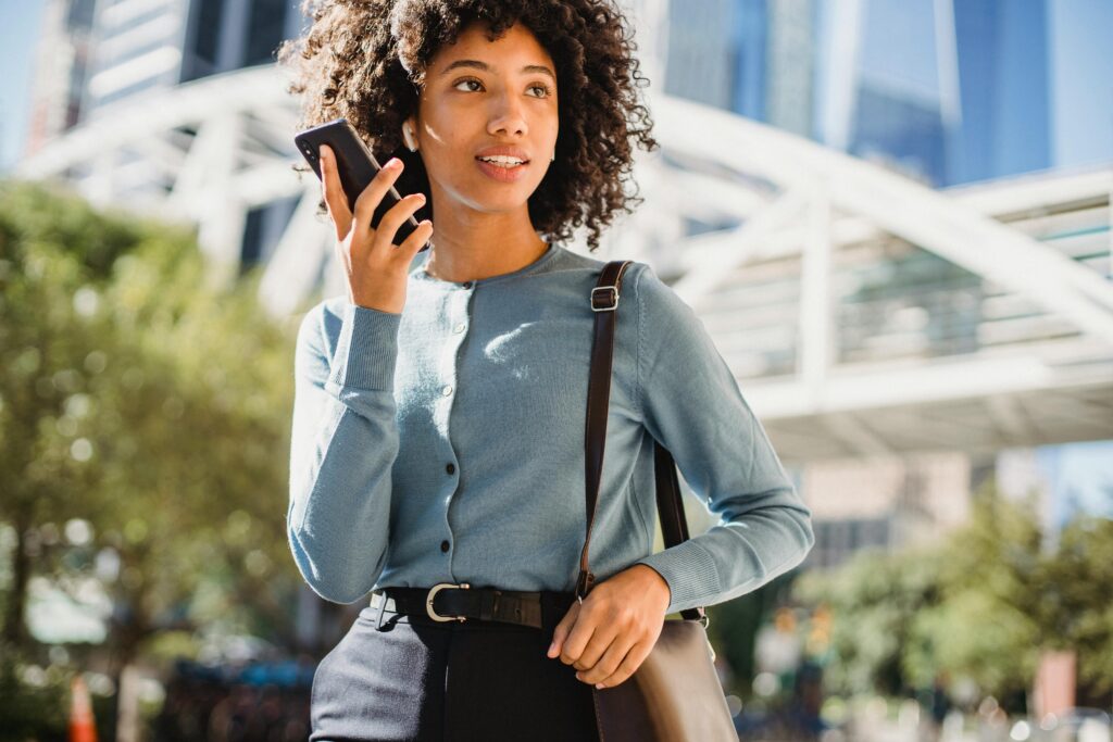 Is Crypto Safe for Women Who Want to Invest A young woman with curly hair talks on her smartphone in an urban outdoor setting.