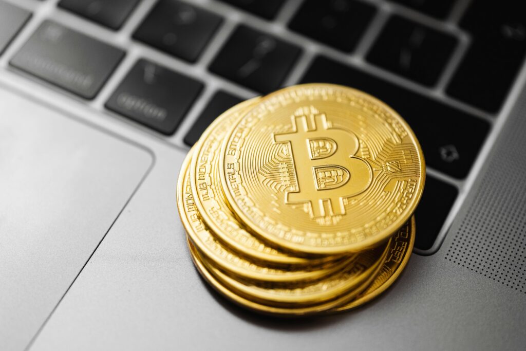 How Is Crypto Created and What Makes It Grow Gold bitcoins stacked on a laptop keyboard symbolizing digital currency and blockchain technology.