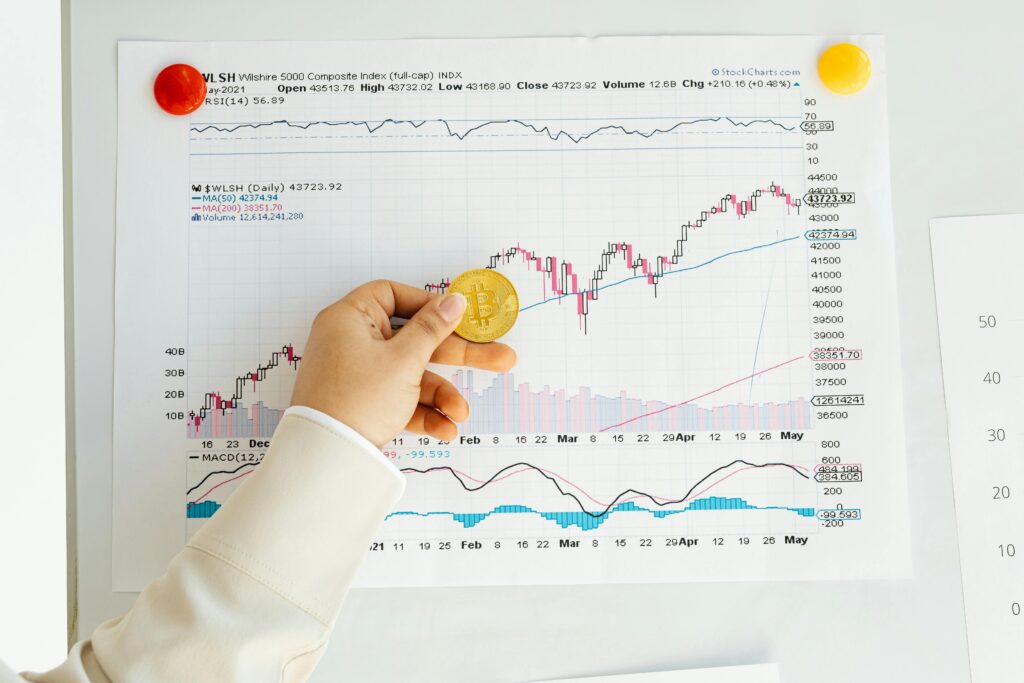 Is Bitcoin's Bull Run Back After Its $82,000 Recovery A hand holding a Bitcoin coin in front of a stock market chart, symbolizing analysis and finance.