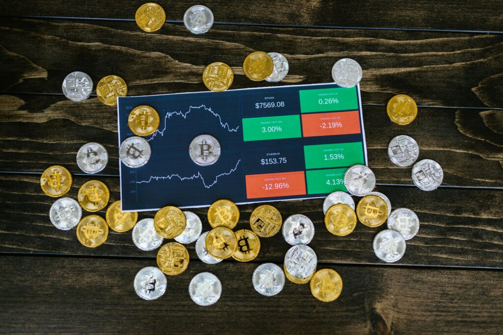 How Dollar Cost Averaging Takes the Stress Out of Crypto Bitcoin coins scattered around a stock chart on a dark wooden table, symbolizing cryptocurrency investment.