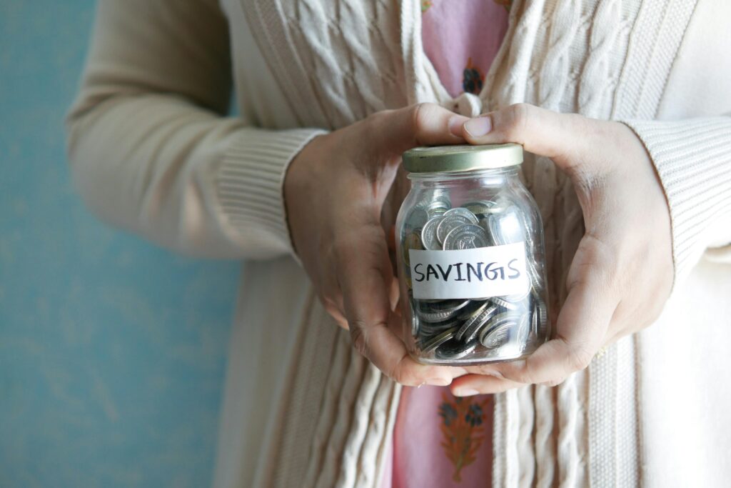 How Much Should You Invest in Crypto as a Beginner Woman holding a jar labeled 'savings' filled with coins, representing financial savings.