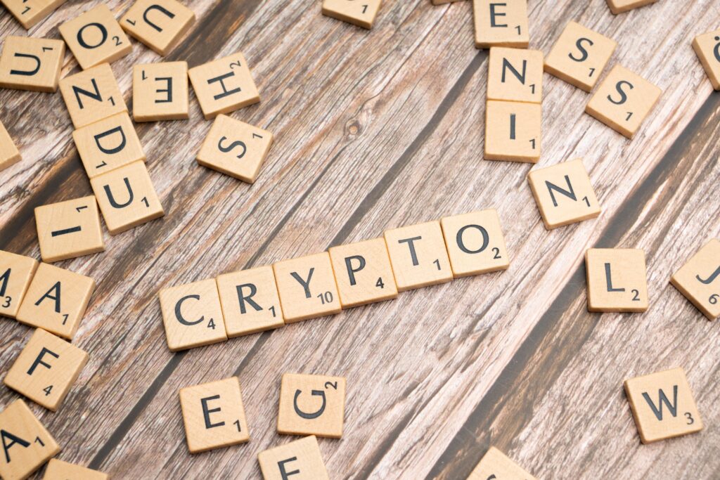 Wooden letter tiles spelling 'Crypto' creatively arranged on a rustic wood surface.