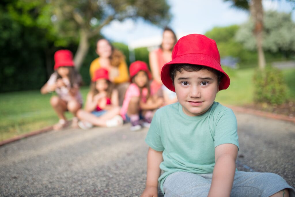 Group of children playing outdoors in summer wearing red hats, creating a joyful vibe.